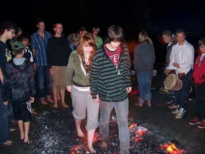 Two teens holding hands as they walk across fire coals together