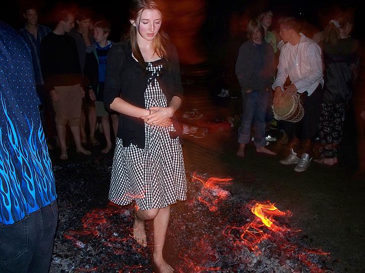 A young woman walks serenely across glowing coals