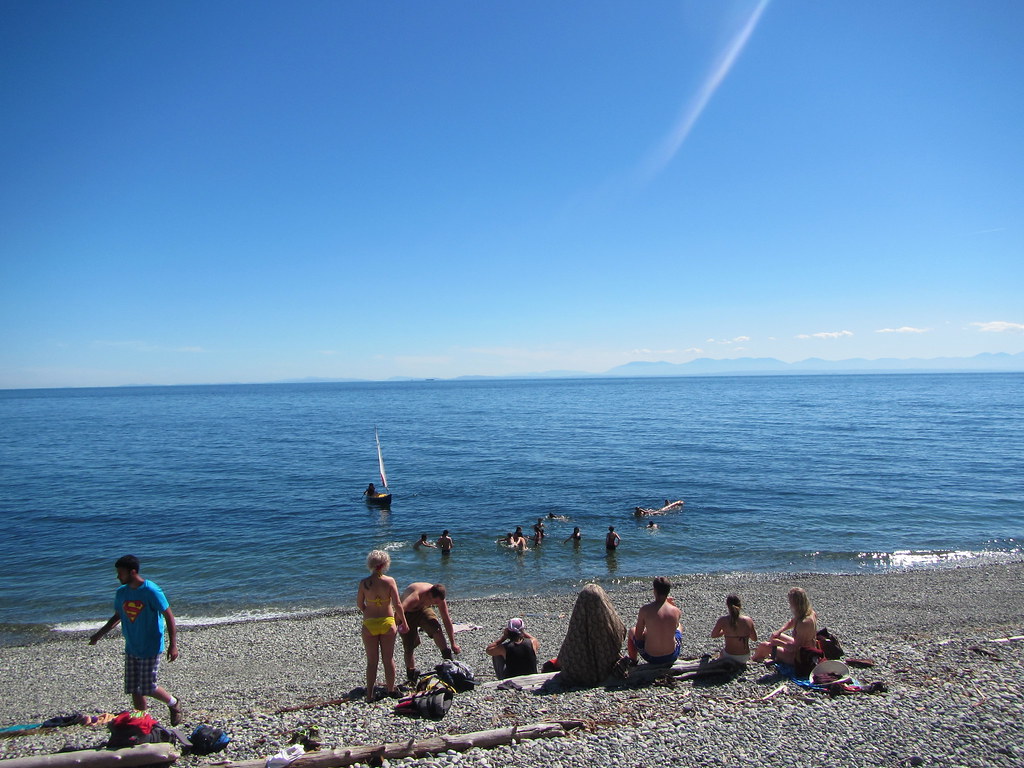 Beach scene with sailboat and youth swimming in the ocean