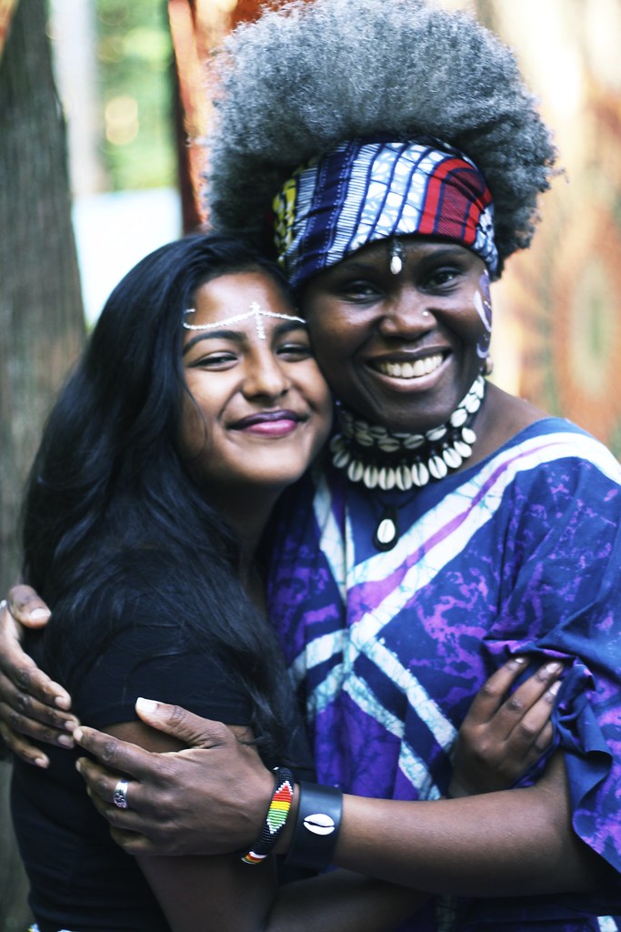Elder and young person embrace during a rites of passage ceremony, adorned with face paint