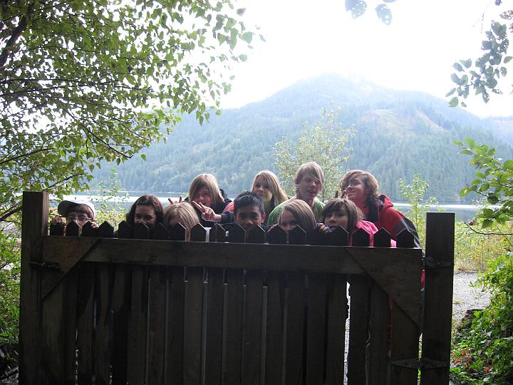 Group of youth peeking over a fence with mountains behind